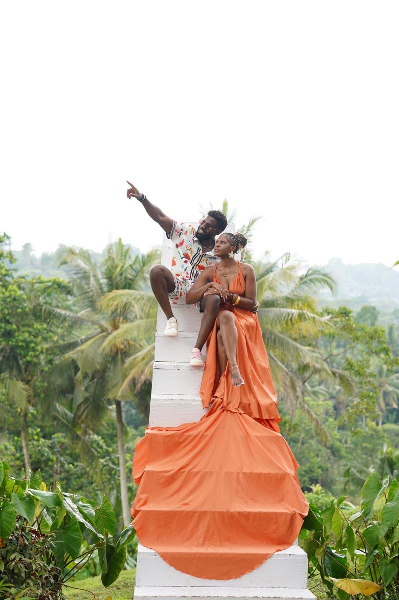 Kayla in a flowing orange gown on a white plinth